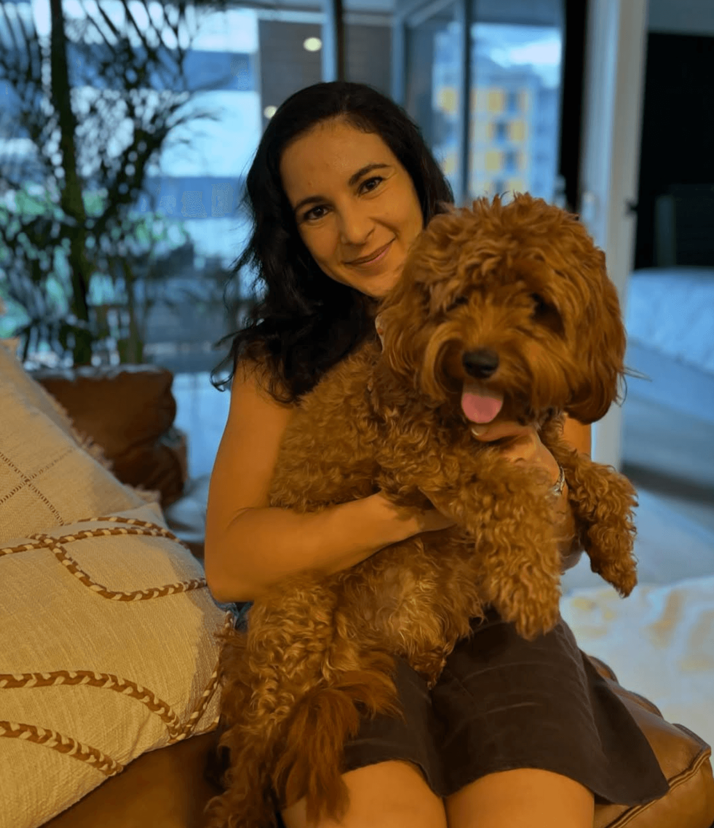 Nikki at home on the couch with a relaxed apricot cavoodle